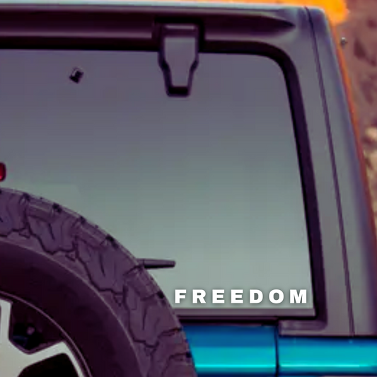 Matte White Vinyl Decal that says Freedom on the rear window of a blue jeep with a hard top.