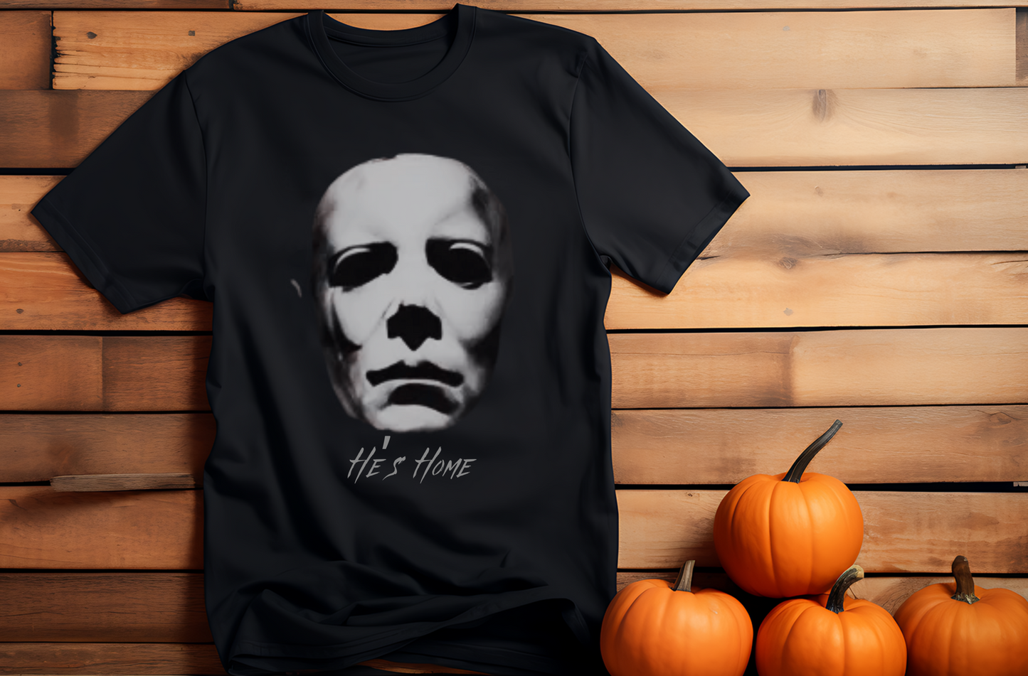 He's Home Black Tee with horror movie slasher michael myers mask fading into the background. Halloween pumpkins on the side