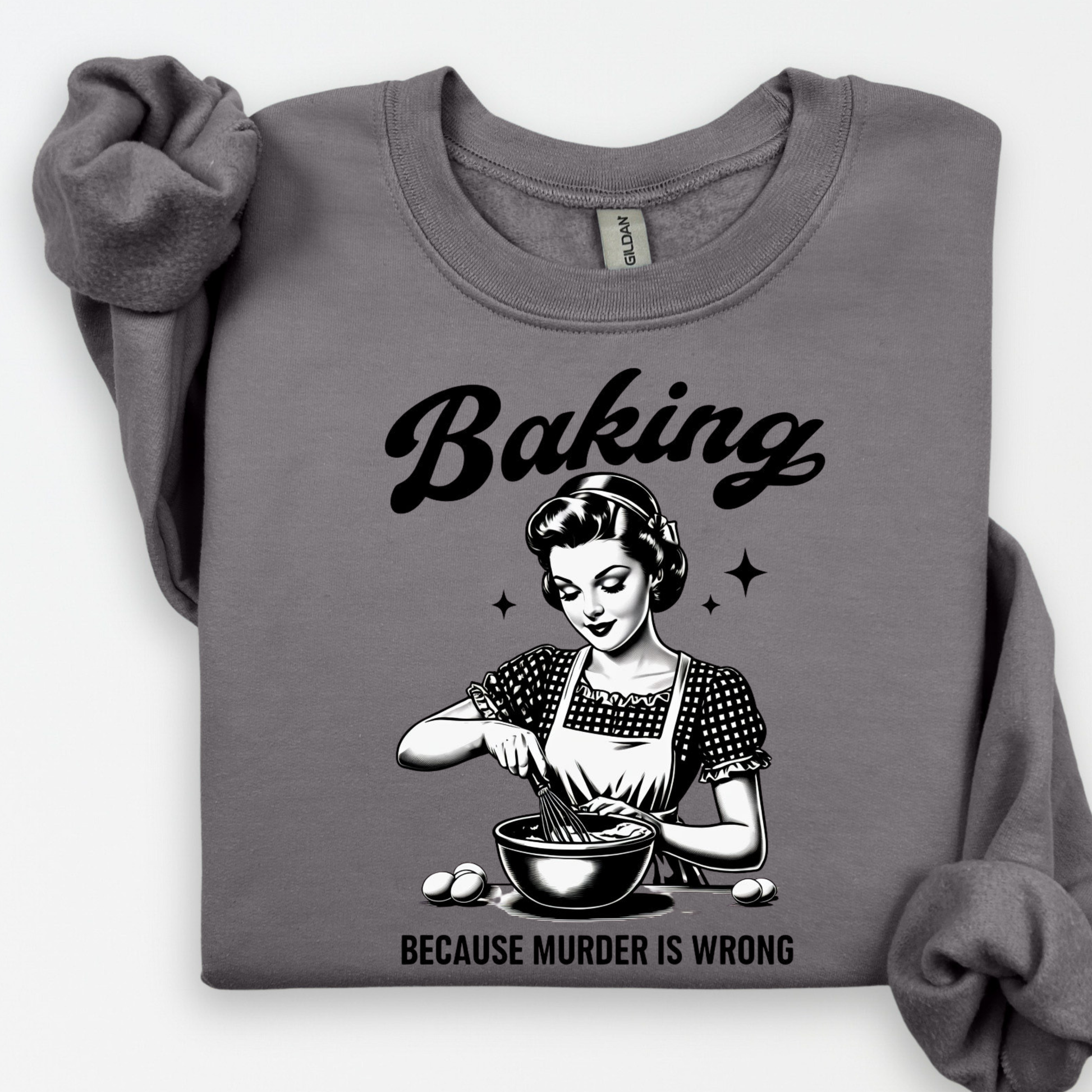 Gray sweatshirt with a graphic of a woman baking and text 'Baking because murder is wrong' on a white background.