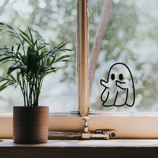 Matte Black double middle finger ghost sticker on a window near a plant where the ghost is flipping off the plant. 