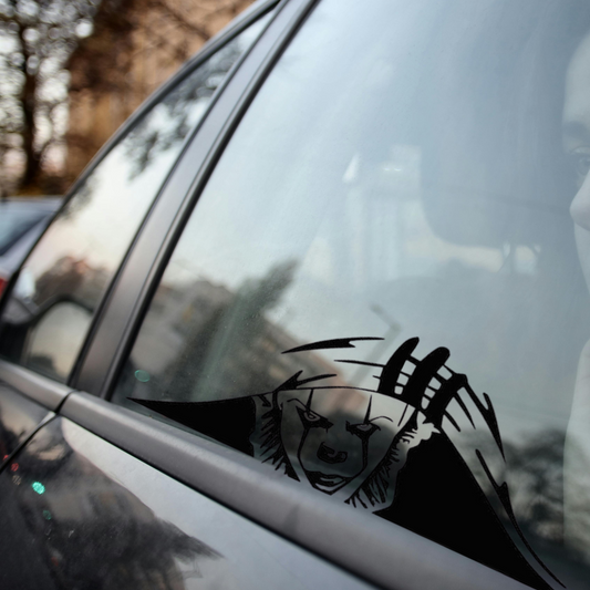 Car window with a black bear decal on a blurred outdoor background