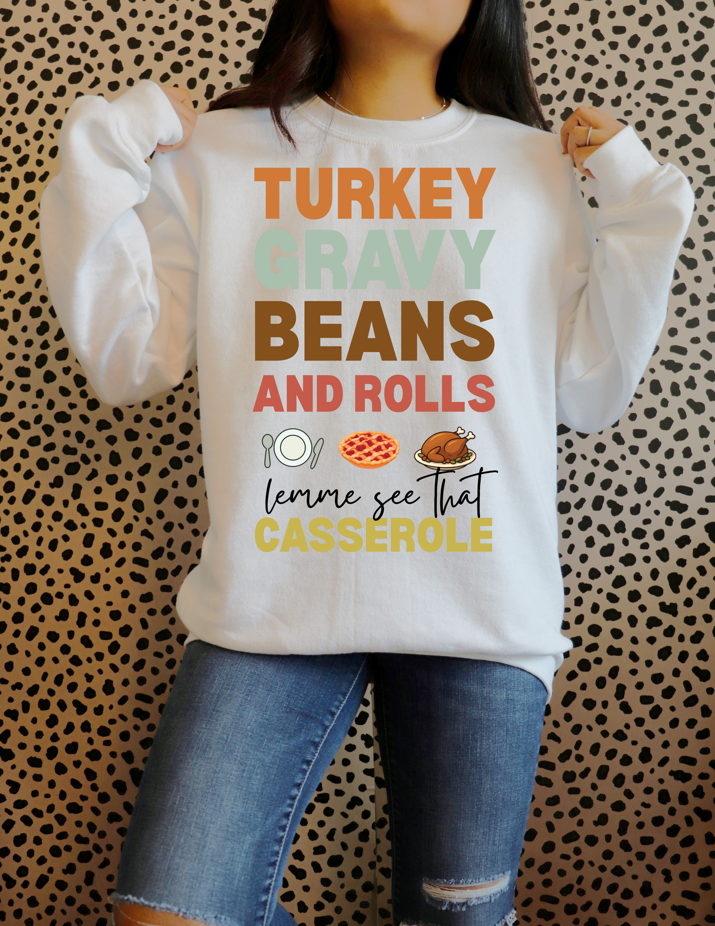 Person wearing a white sweatshirt with colorful text and graphics against a patterned background