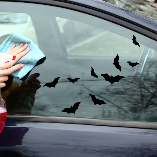 Matte black bats flying on a clear window on a car with a blue sedan