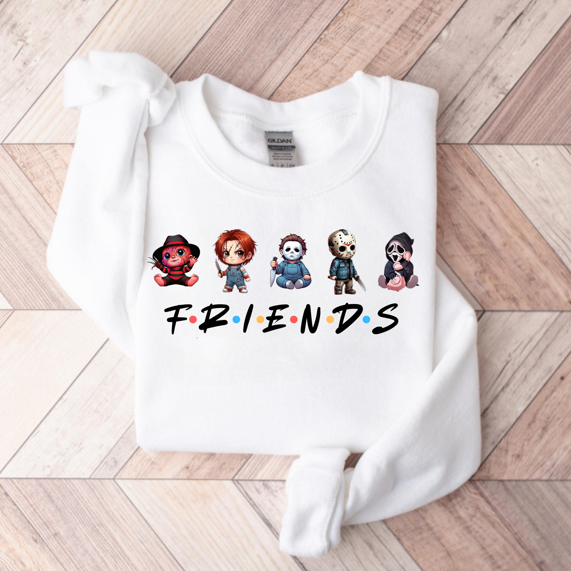 White sweatshirt with cartoon character design and 'FRIENDS' text on a wooden floor.
